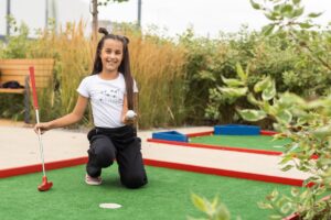 young girl playing mini golf